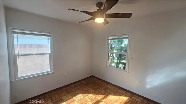 an empty room with windows and fan