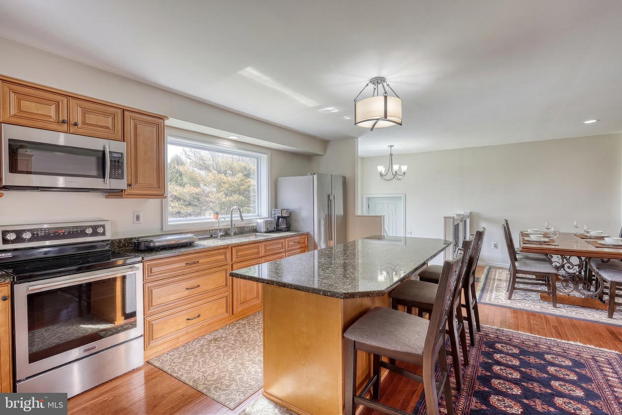 12534 Mt Olivet Road Felton, PA 17322 - Photo 14 of 75 a kitchen with granite countertop a stove a oven a dining table and chairs with wooden floor