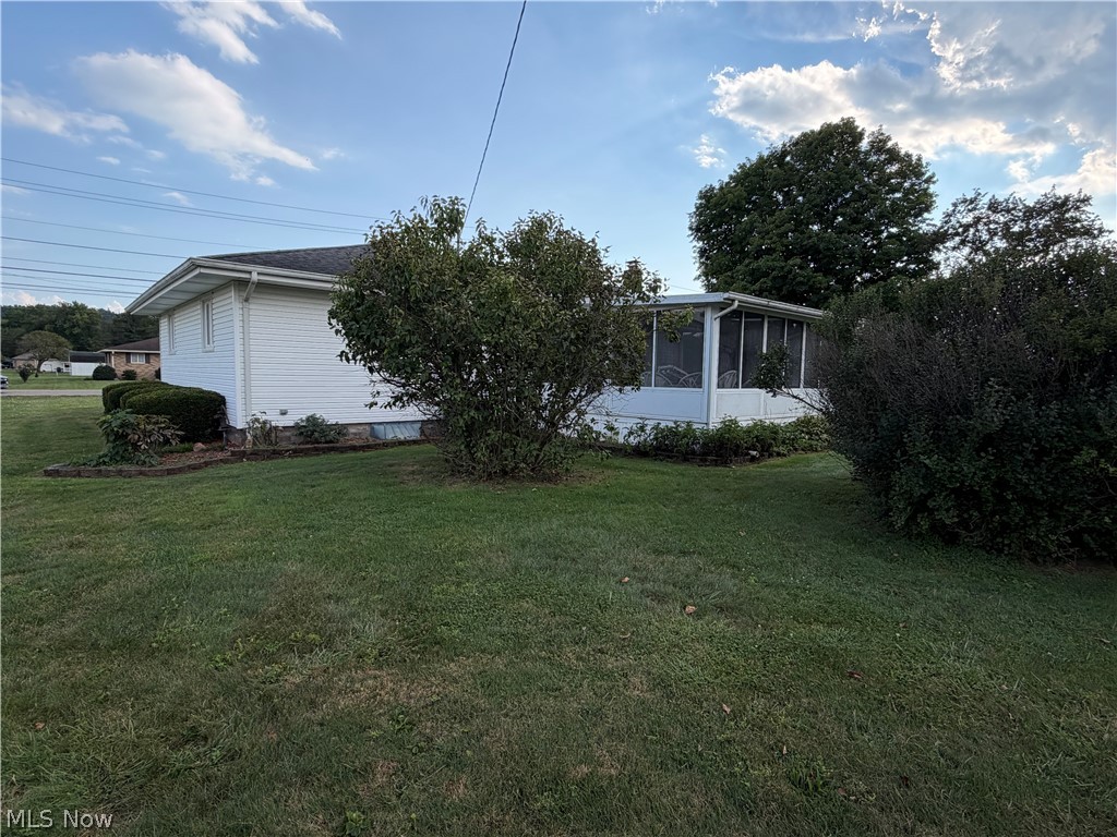 6063 East State Road Newcomerstown, OH 43832 - Photo 26 of 31 White exterior siding with a screened-in porch, surrounded by mature landscaping and a grass lawn