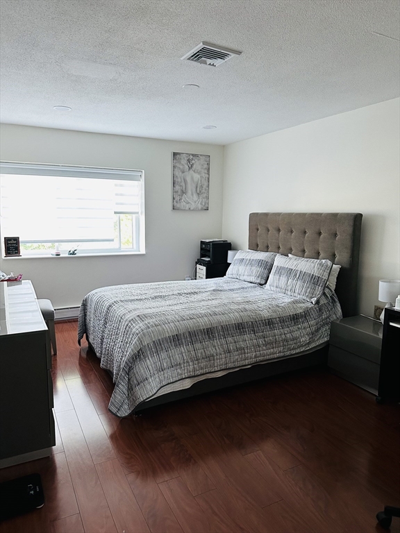 1202 Greendale Avenue, Unit 135 Needham, MA 02492 - Photo 6 of 6 a bedroom with a bed wooden floor and window