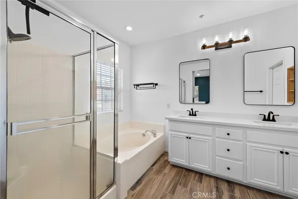 a bathroom with a double vanity sink a mirror a bathtub and shower