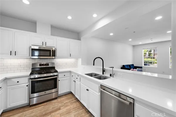 a kitchen with white cabinets stainless steel appliances and wooden floor