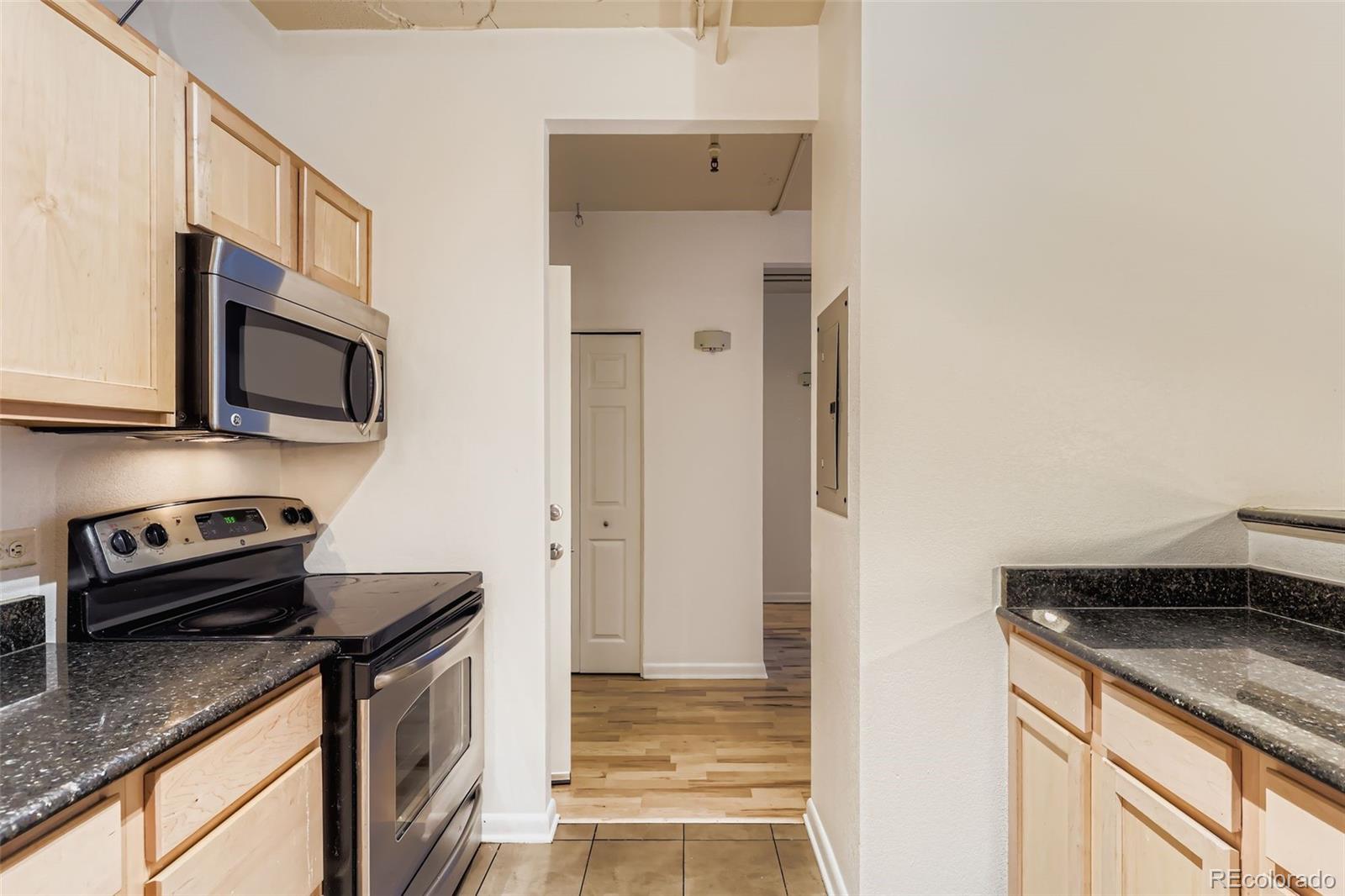 444 17th Street, Unit 404 Denver, CO 80202 - Photo 7 of 37 a kitchen with stainless steel appliances granite countertop a refrigerator a stove and a sink with wooden floor
