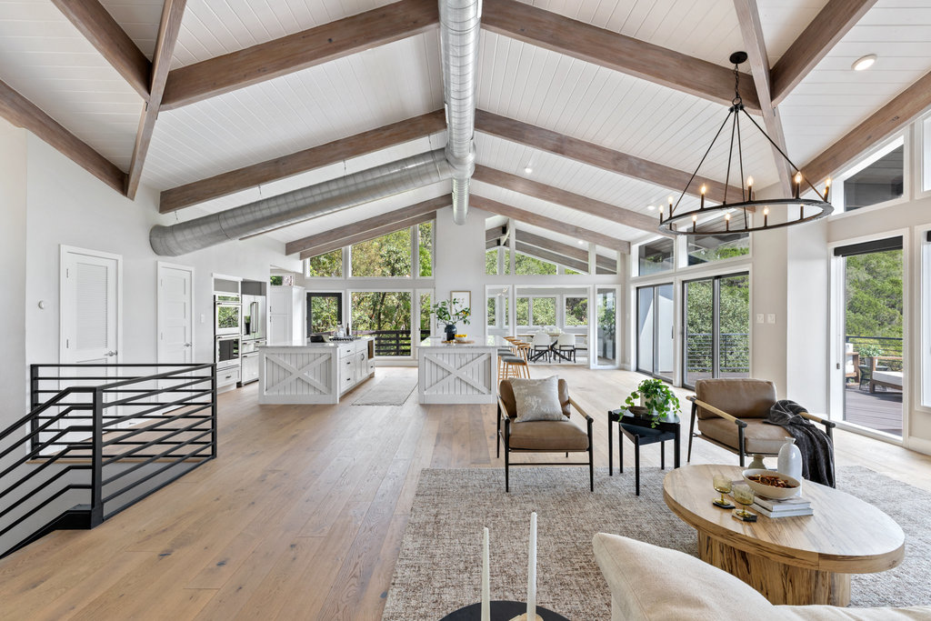 Living room with high vaulted ceiling, light wood finished floors, beam ceiling, and a chandelier