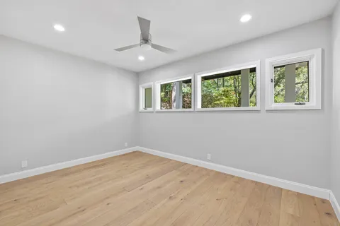 a view of an empty room with a window and wooden floor