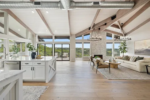 a living room with furniture large windows and wooden floor