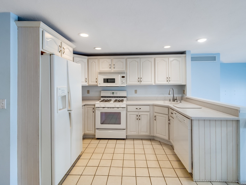 16 Milford Street, Unit 9 Hull, MA 02045 - Photo 9 of 42 a kitchen with white cabinets a sink and white appliances