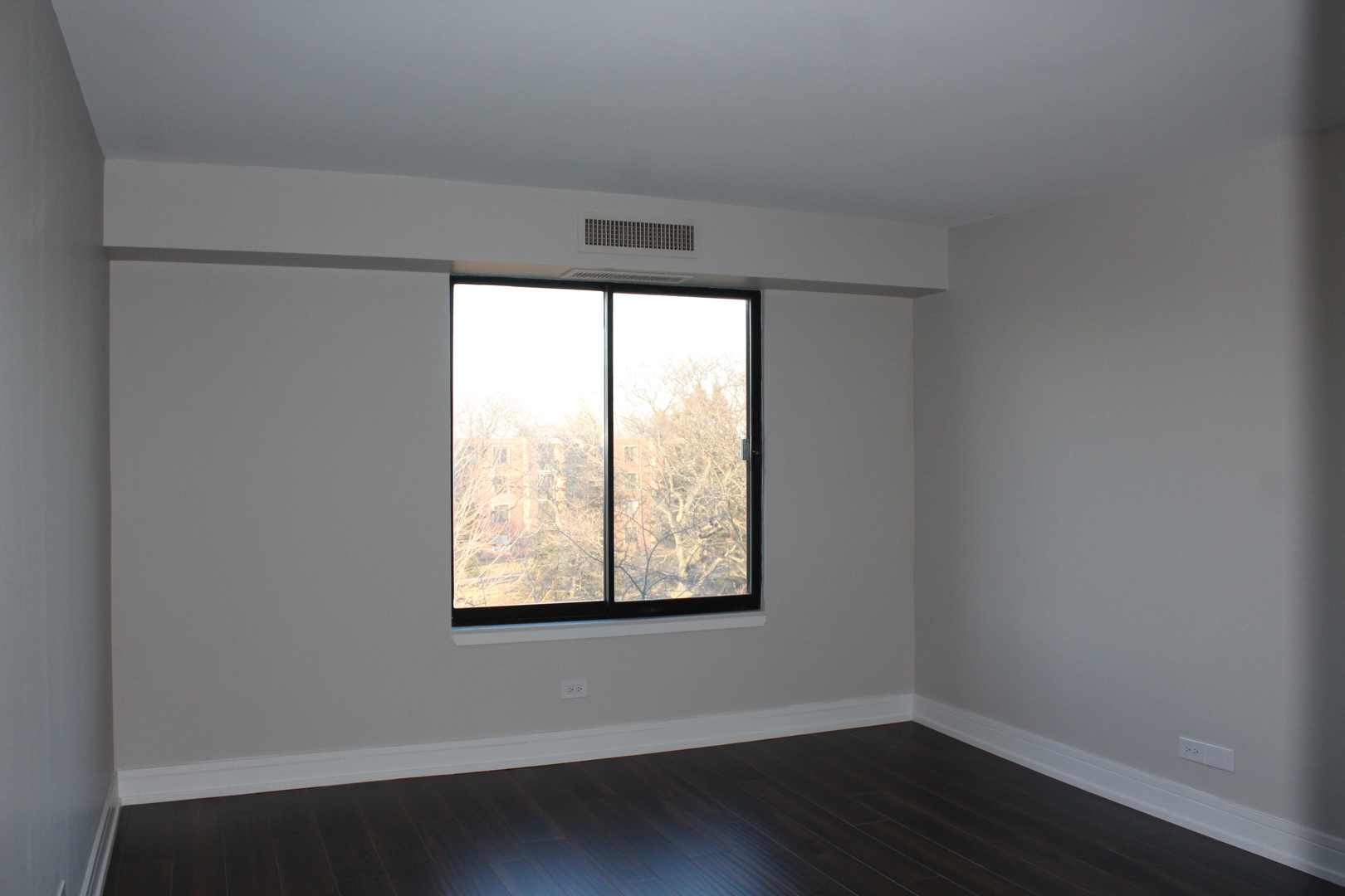 1605 East Central Road, Unit 413B Arlington Heights, IL 60005 - Photo 8 of 15 an empty room with wooden floor and windows
