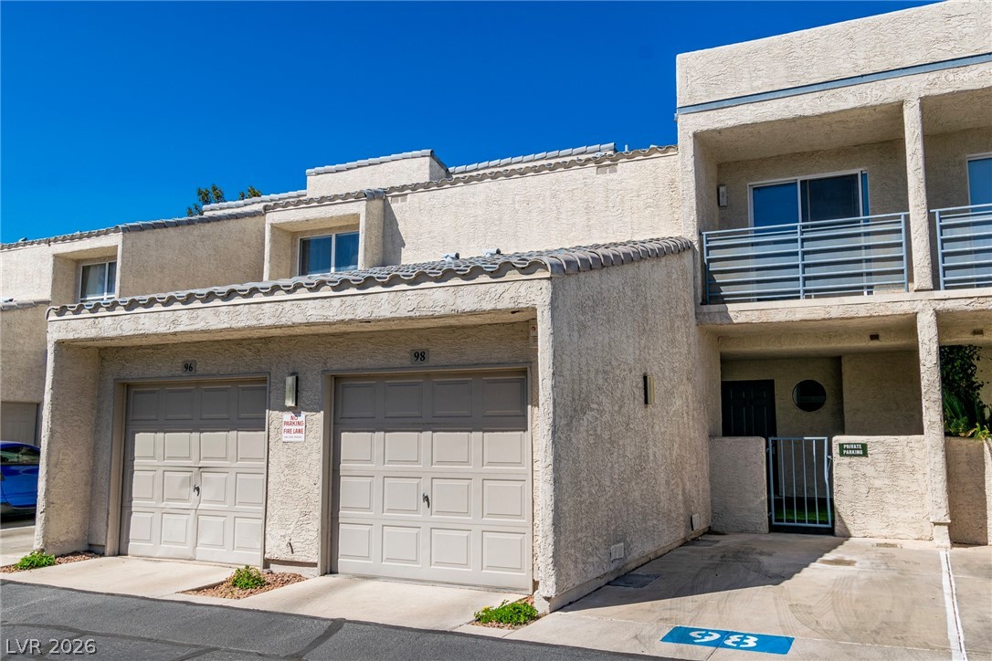 6250 West Flamingo Road, Unit 98 Las Vegas, NV 89103 - Photo 1 of 40 View of front facade featuring a balcony, a gate, stucco siding, and an attached garage
