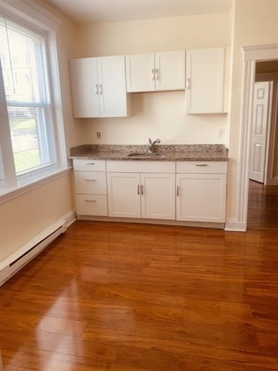 4 Hancock Street, Unit 2 Malden, MA 02148 - Photo 3 of 5 a large white kitchen with granite countertop white cabinets and wooden floor