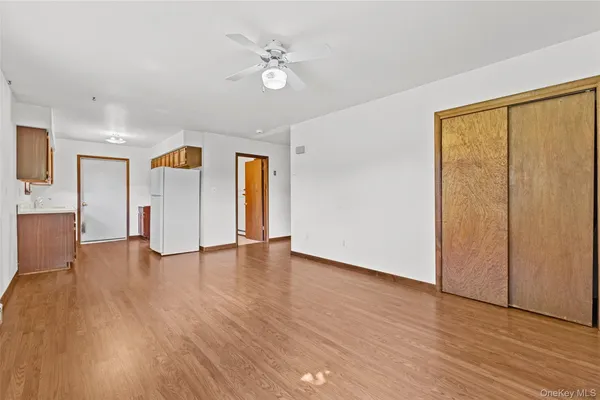 a view of an empty room with wooden floor and a window