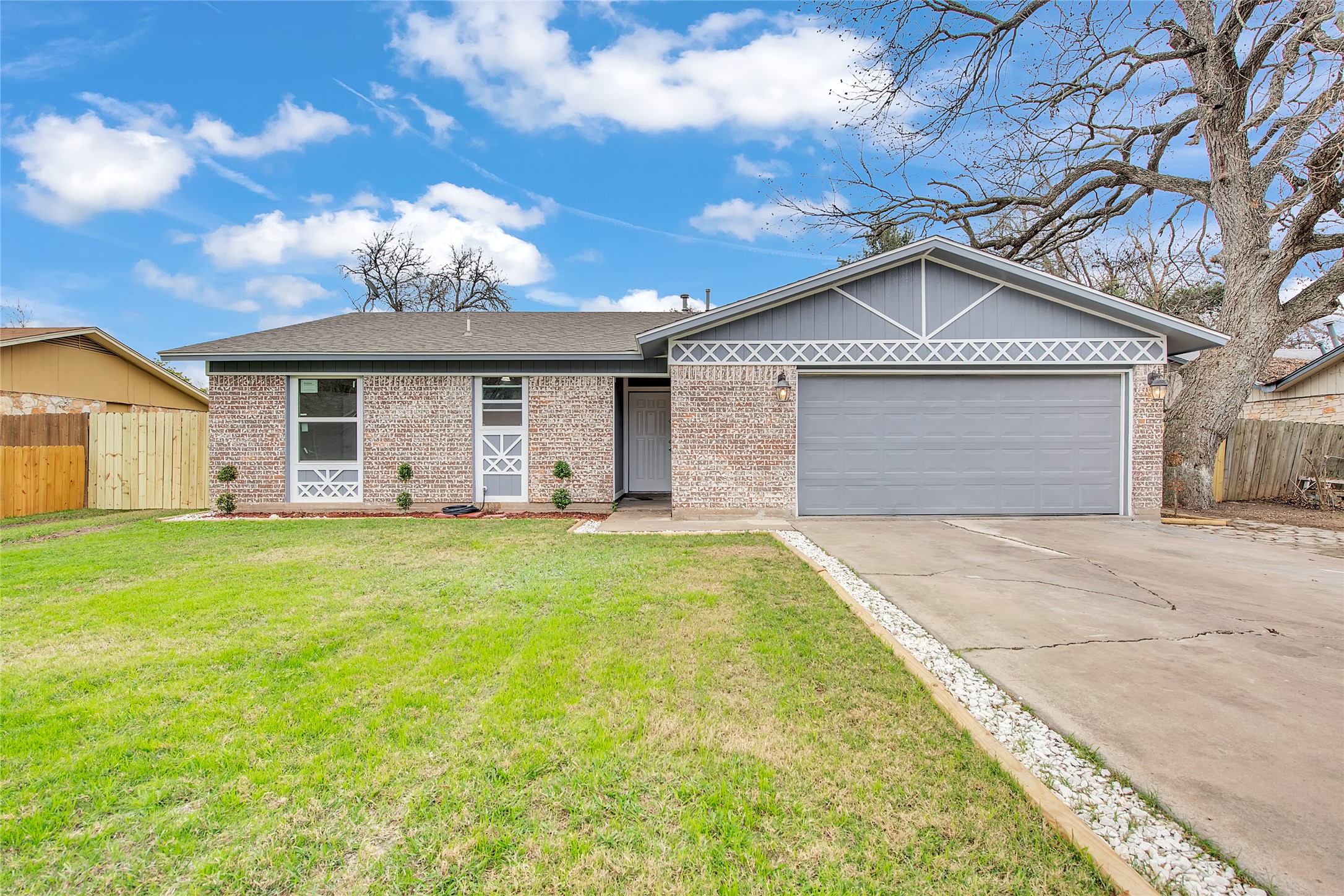 A well-kept front yard complements this single-story residence, featuring a two-car garage and a classic brick and siding exterior.