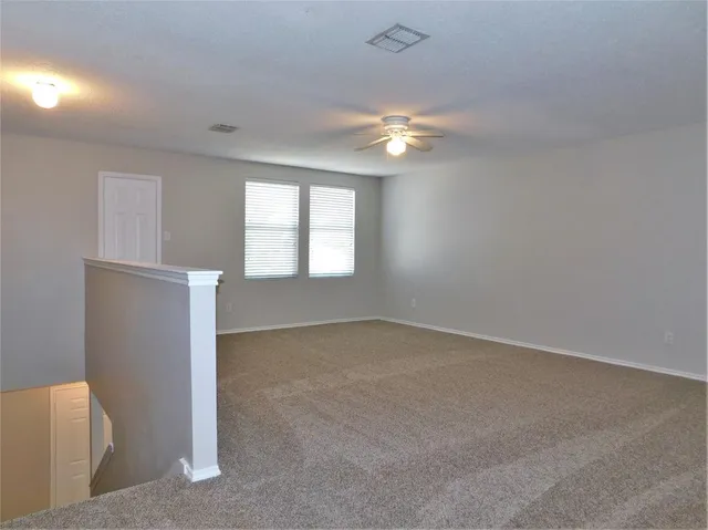 an empty room with windows and chandelier fan