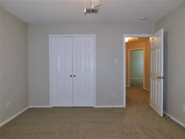 a view of an empty room with closet and a bathroom