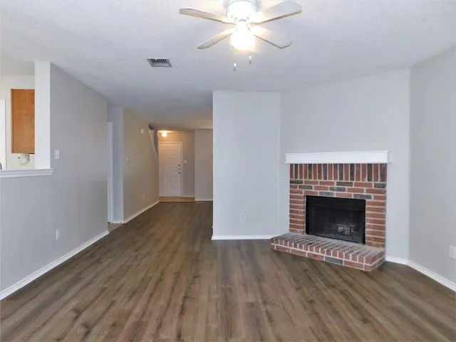 a view of an empty room with wooden floor fireplace and a window