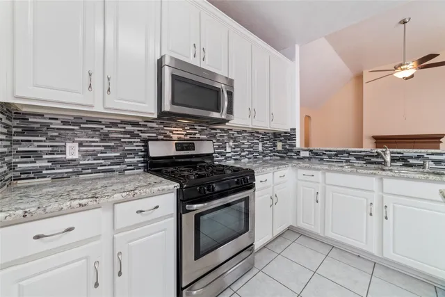 a kitchen with granite countertop white cabinets and appliances