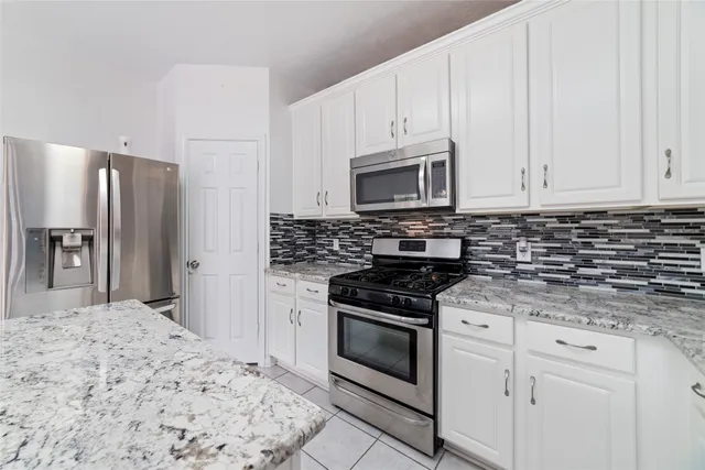 a kitchen with granite countertop a stove sink and refrigerator