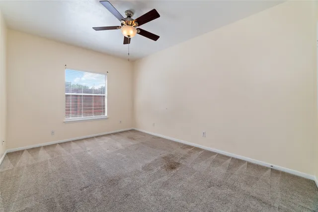 an empty room with a window and a fan