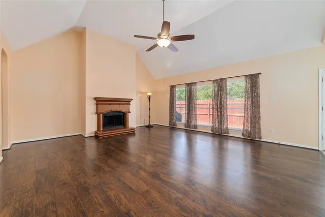 an empty room with wooden floor fireplace and windows