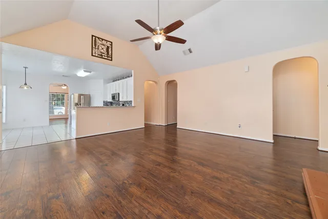 a view of empty room with wooden floor and ceiling fan