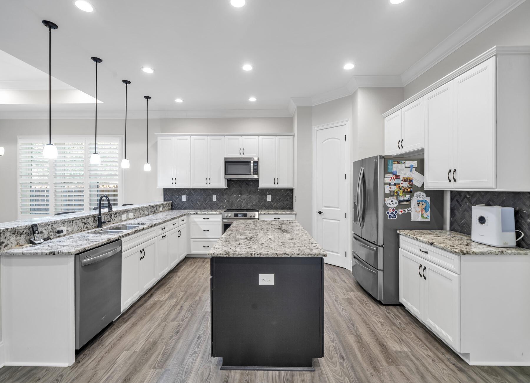 a large kitchen with stainless steel appliances kitchen island granite countertop a stove a sink dishwasher and a refrigerator with wooden floor