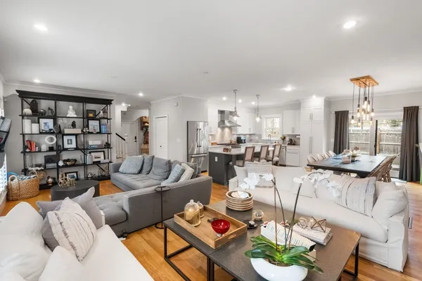 a living room with furniture kitchen view and a large window