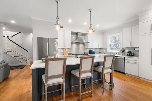 a kitchen with stainless steel appliances kitchen island granite countertop a refrigerator a stove a sink and a dining table with wooden floor