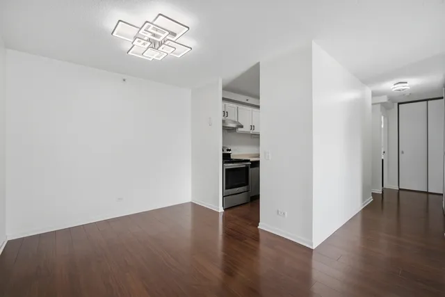 an empty room with wooden floor and kitchen