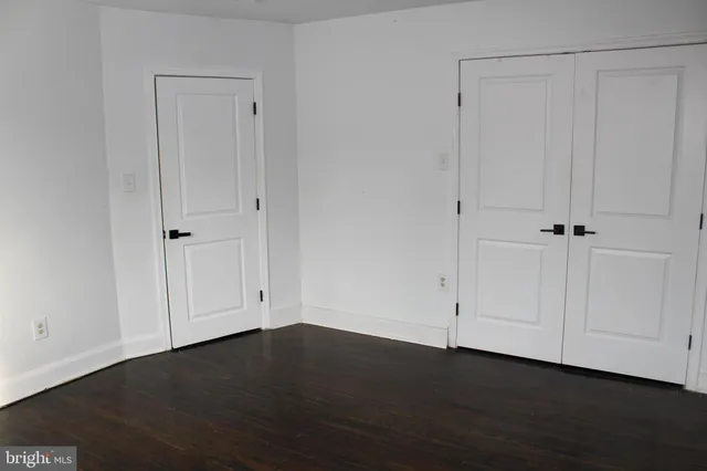 a view of a hallway with wooden floor and a bathroom