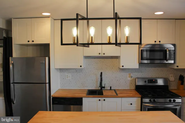 a kitchen with stainless steel appliances kitchen island granite countertop a refrigerator a sink and a stove