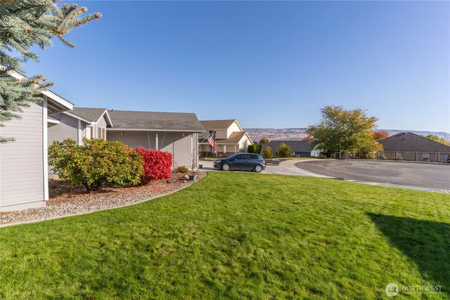 a view of a house with a yard and table and chairs under an umbrella