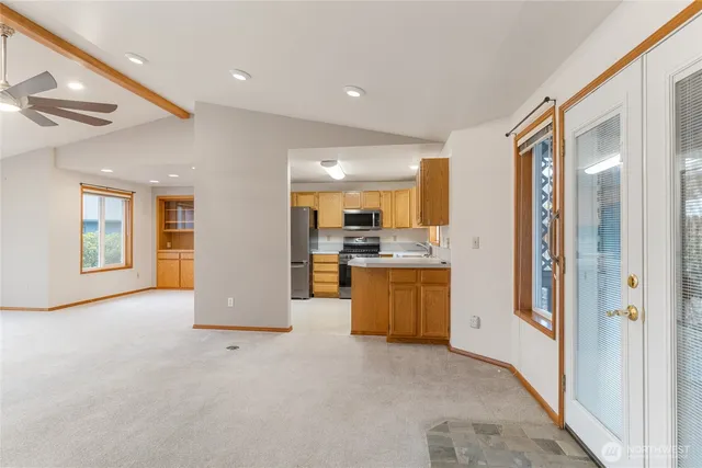 a view of an empty room with a window and kitchen view