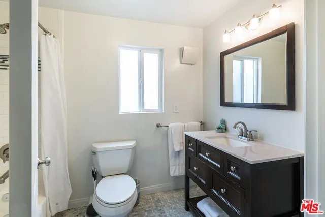 a bathroom with a toilet sink vanity and mirror