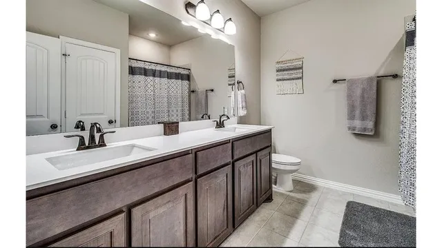 a bathroom with a double vanity sink mirror and toilet