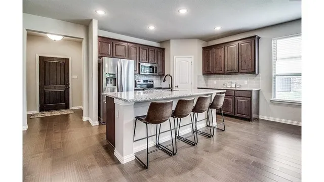 a kitchen with stainless steel appliances granite countertop a refrigerator and a stove top oven