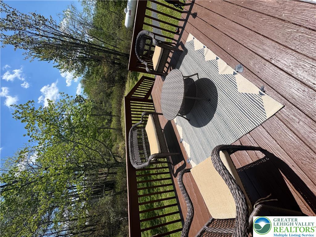 2742 Long Pond Road Long Pond, PA 18334 - Photo 13 of 57 A spacious outdoor deck with wood flooring provides a relaxing retreat amidst lush greenery and blue skies.