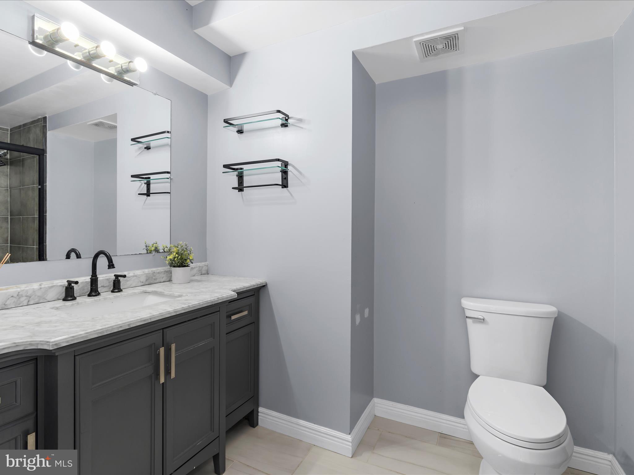 15533 Thompson Road Silver Spring, MD 20905 - Photo 26 of 76 a bathroom with a granite countertop sink a toilet and a mirror