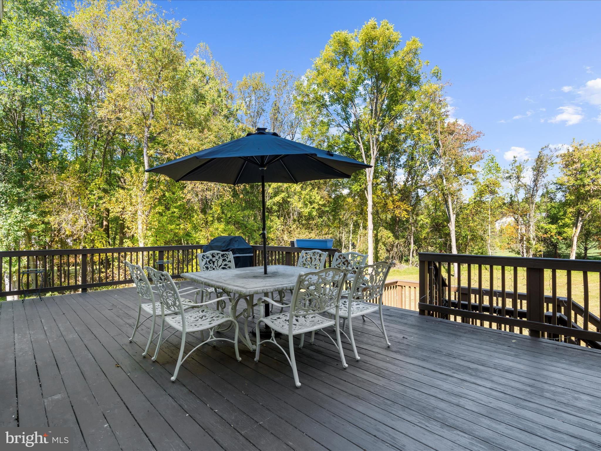 15533 Thompson Road Silver Spring, MD 20905 - Photo 53 of 76 a view of a roof deck with table and chairs under an umbrella with wooden floor