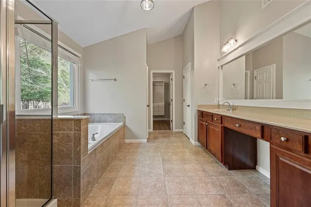a spacious bathroom with a granite countertop sink mirror and bathtub