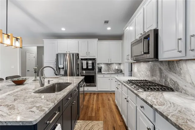 a kitchen with granite countertop a sink stainless steel appliances and cabinets