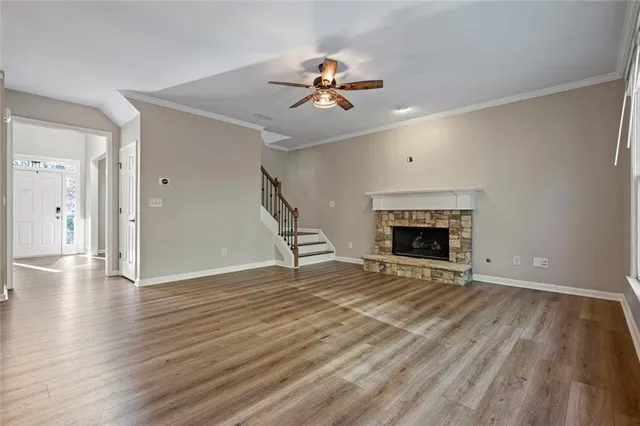 a view of an empty room with wooden floor fireplace and a window