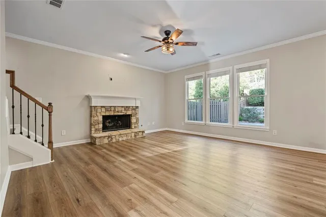 a view of an empty room with wooden floor fireplace and a window