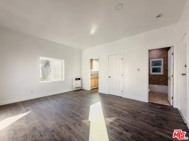 an empty room with wooden floor & windows and bathroom