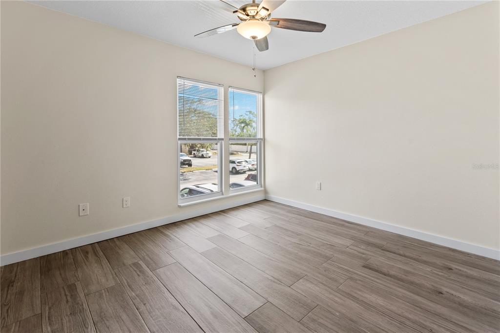 3405 Clark Road, Unit 205 Sarasota, FL 34231 - Photo 13 of 28 an empty room with wooden floor chandelier fan and windows