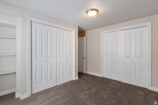2350 South Highway 89, Unit 4 Perry, UT 84302 - Photo 16 of 30 Unfurnished bedroom featuring dark colored carpet and multiple closets