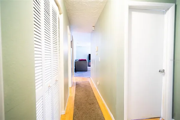 a view of a hallway with wooden floor and a bathroom