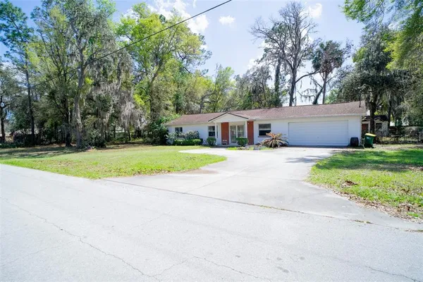 a view of house with yard and trees in the background