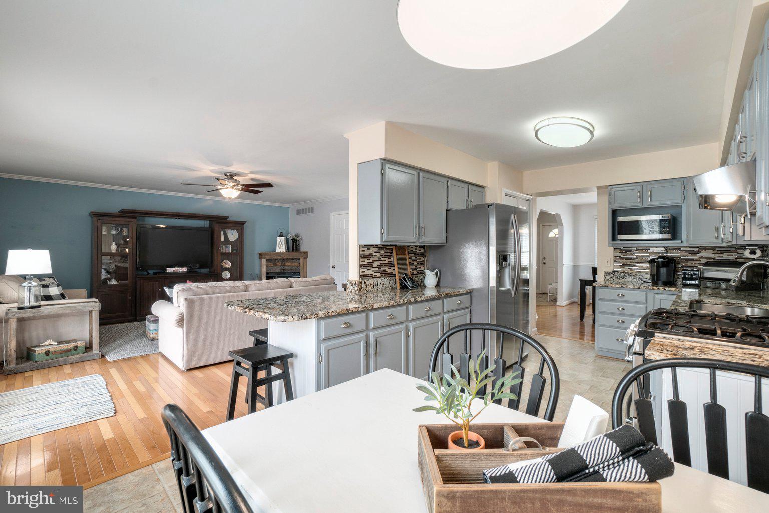 1617 Cape May Road Baltimore, MD 21221 - Photo 12 of 37 a kitchen with stainless steel appliances kitchen island granite countertop a stove a sink a dining table and chairs with wooden floor