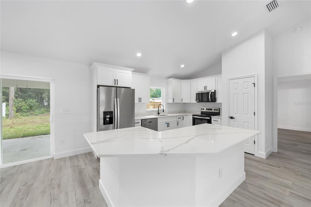 6052 Northwest 53rd Street Road Ocala, FL 34482 - Photo 14 of 26 a large white kitchen with wooden floor and large window