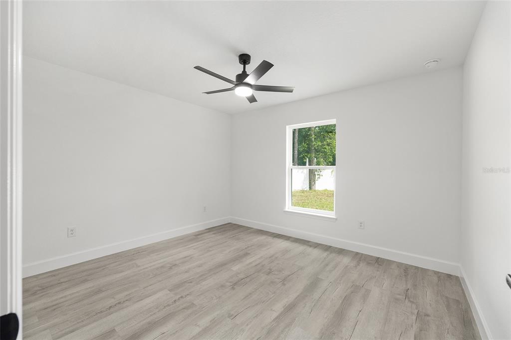 6052 Northwest 53rd Street Road Ocala, FL 34482 - Photo 22 of 26 an empty room with wooden floor ceiling fan and window